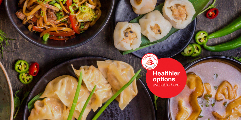Assorted Asian dishes including dumplings, noodles, and vegetables on dining table.